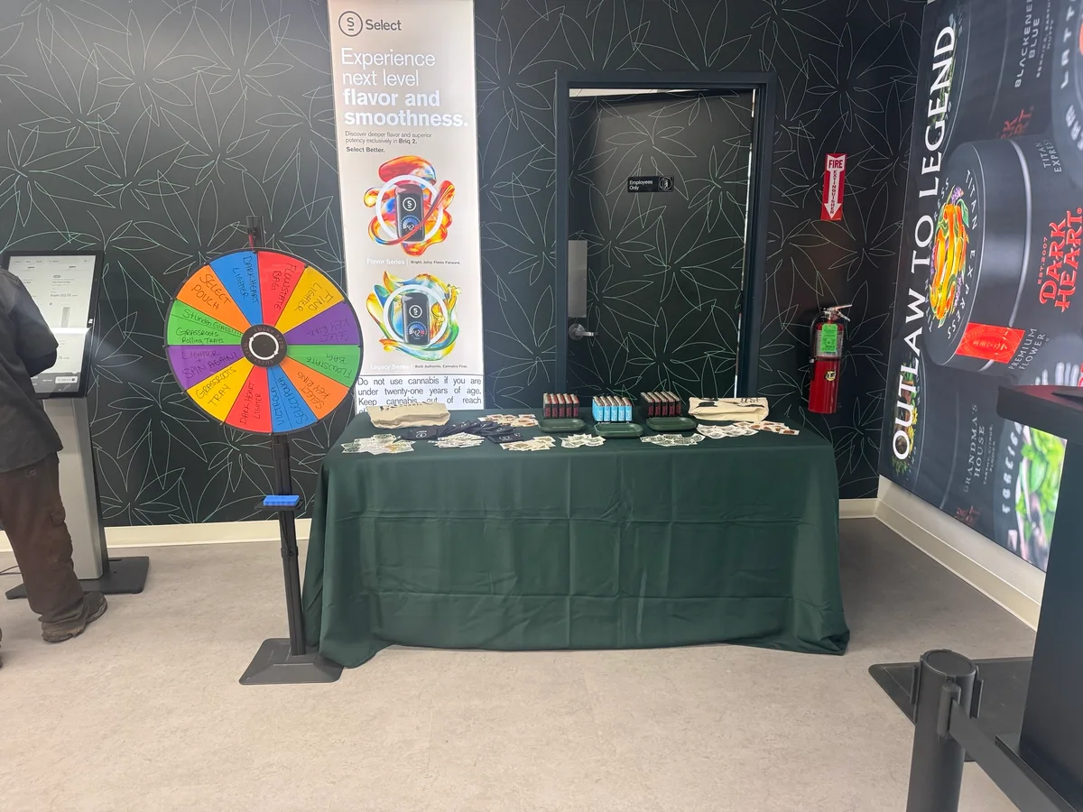 A rainbow-colored prize wheel stands beside a green-draped table set with giveaway items inside the store.