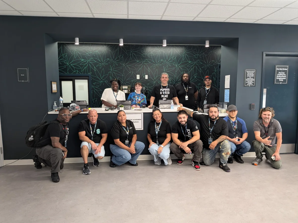 Curaleaf Meriden employees pose together in front of and behind the store's service counter.