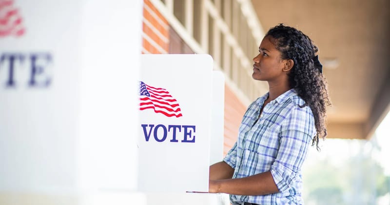 A voter fills out a ballot at a voting booth marked Vote