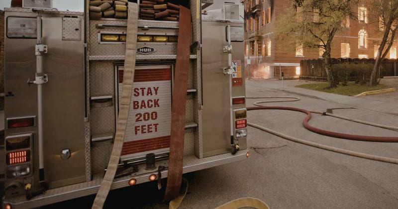 The back of a fire engine with hoses laid out on the street at a fire