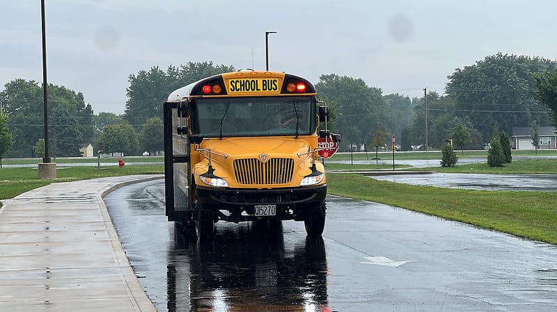 A school bus on a wet road with its stop arm out
